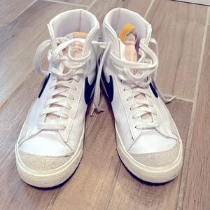 White and black mid-top Nike blazer 77 shoes.